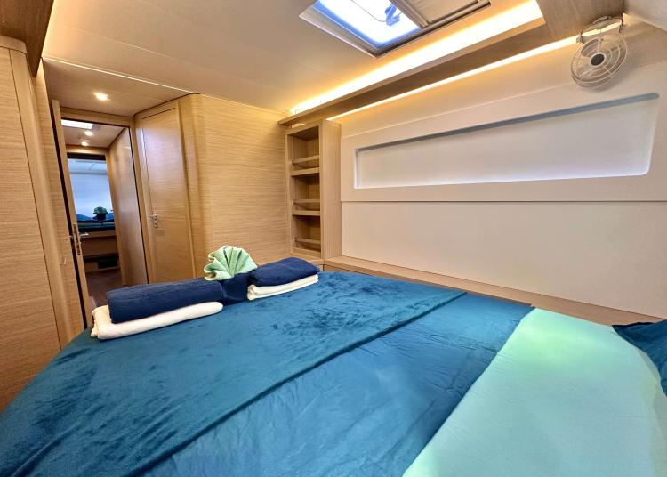 Luxurious cabin interior of 2023 Lagoon 46 yacht with blue bedding and modern design.