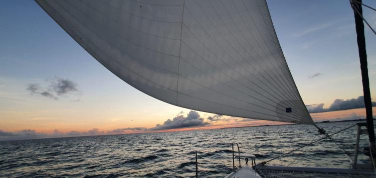 Sailing on a 1999 Fountaine Pajot Bahia 46 catamaran at sunset over the ocean.