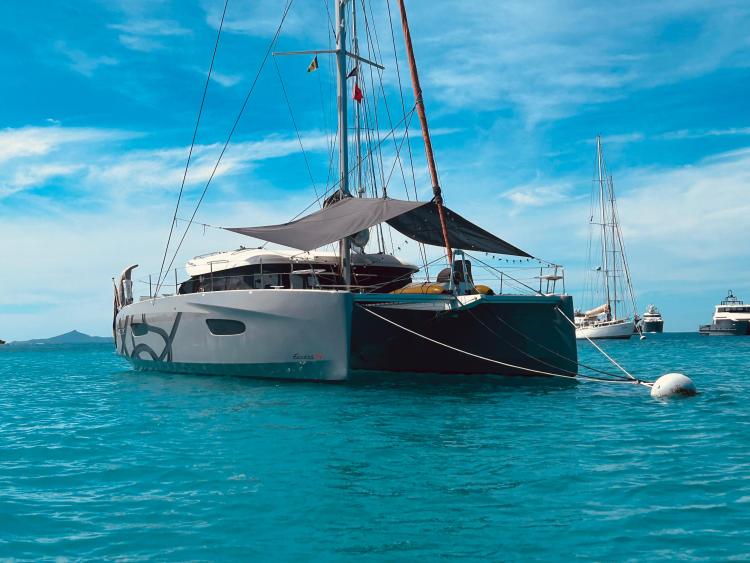 2024 Excess 14 catamaran anchored in clear blue waters under a sunny sky.