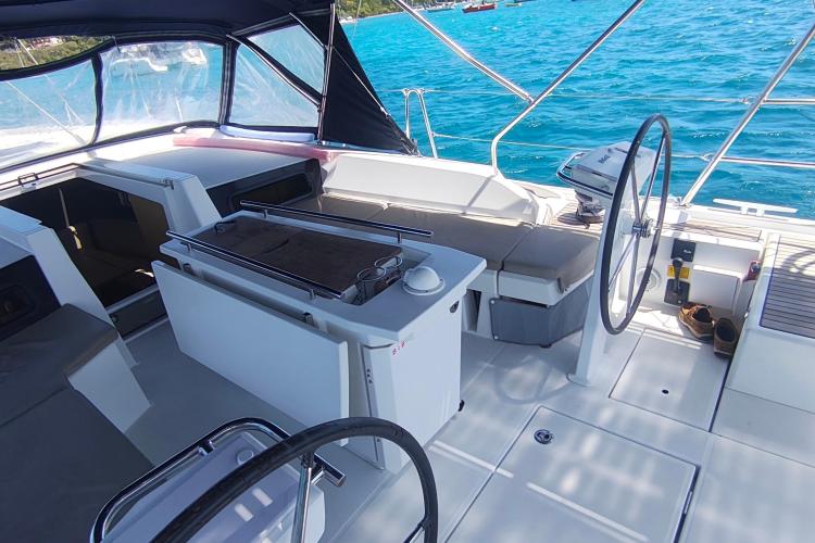 Cockpit of 2019 Beneteau Oceanis 46.1 yacht with steering wheel and seating, on blue water.
