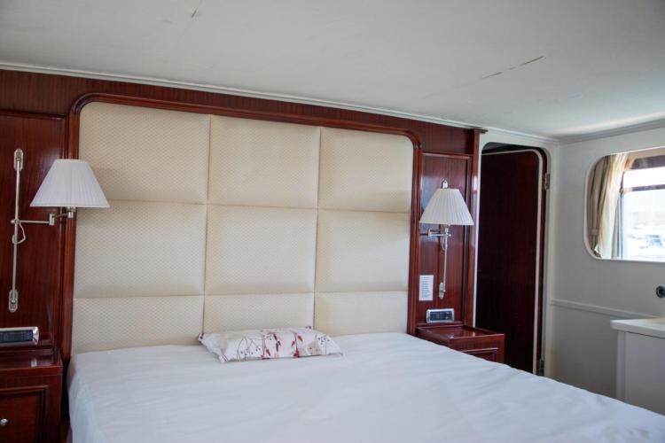 Luxurious bedroom interior on a 1972 Benetti 33 yacht, featuring elegant wood paneling.