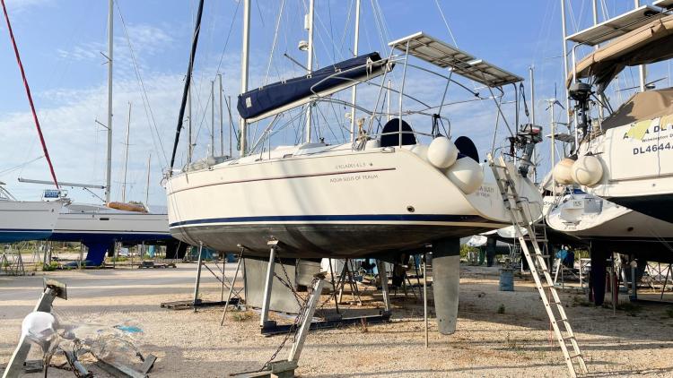 Beneteau Cyclades 43.3 sailboat from 2005 on dry dock with clear sky background.