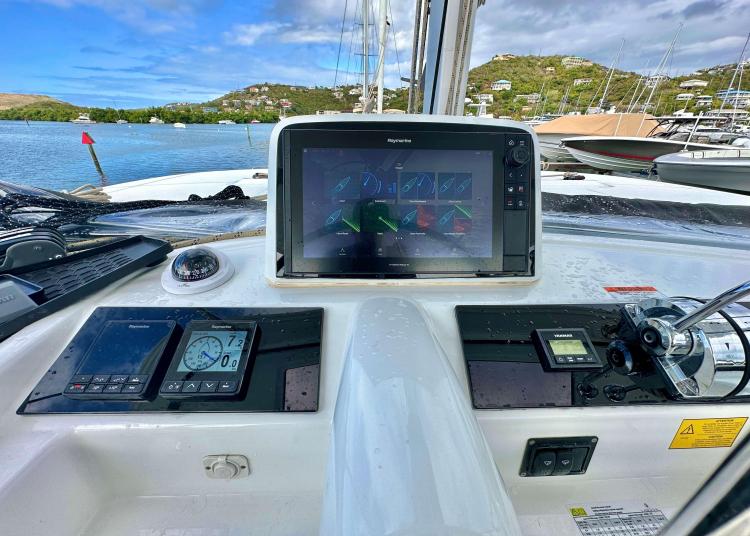 Cockpit of 2023 Lagoon 46 catamaran with navigation instruments and scenic marina view.