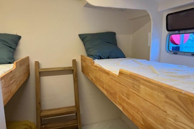Bunk beds in Etoile Marine Maxi Cat 24, 2004 model, with wooden ladder and window.