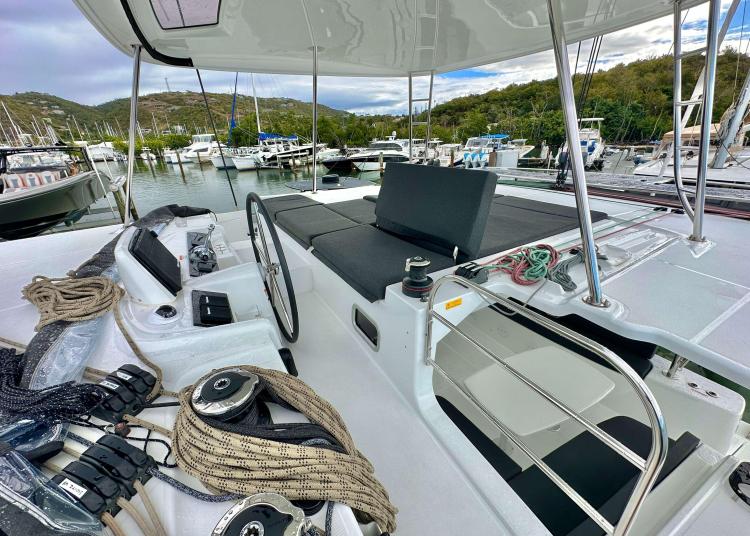 2023 Lagoon 46 yacht deck with helm, ropes, and marina view.