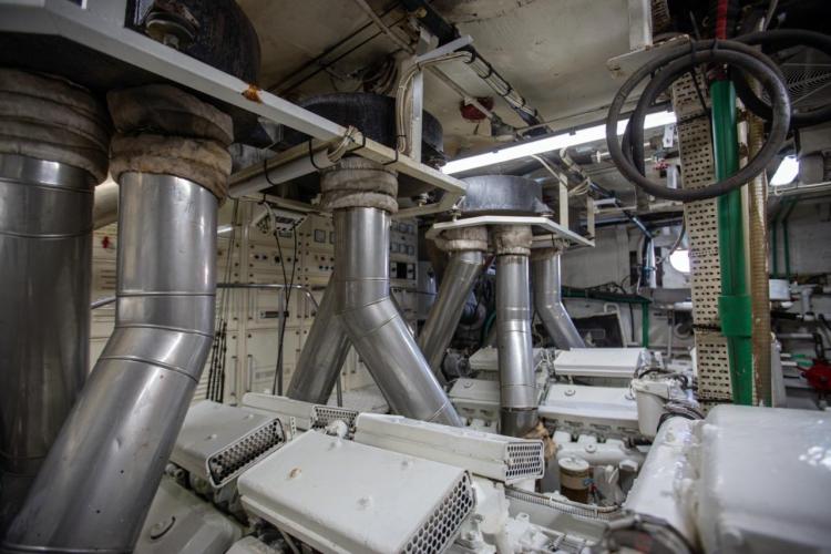Engine room of a 1972 Benetti 33 yacht, featuring complex machinery and exhaust systems.