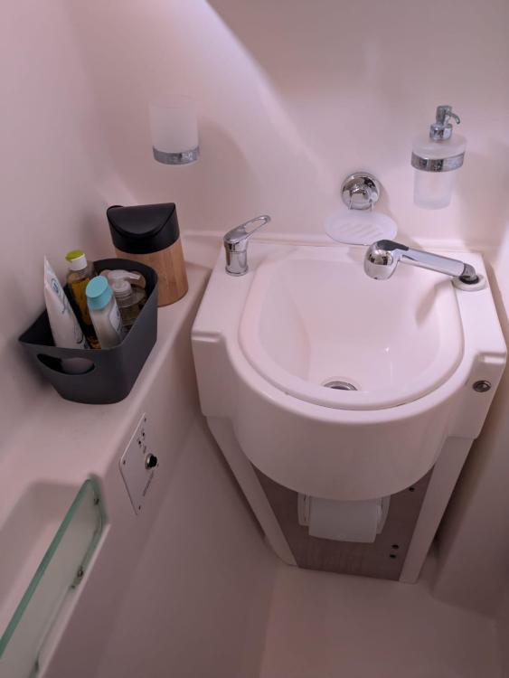 Compact bathroom sink in a 2012 Catana 55 yacht, featuring toiletries and modern fixtures.