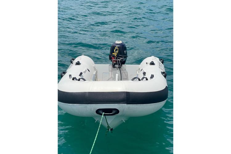 Inflatable dinghy with motor, tethered on water, near Fountaine Pajot Astrea 42 Catamaran, 2023 model.
