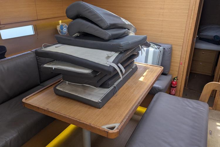 Interior of 2017 Dufour 460 Grand Large yacht with stacked cushions on table.