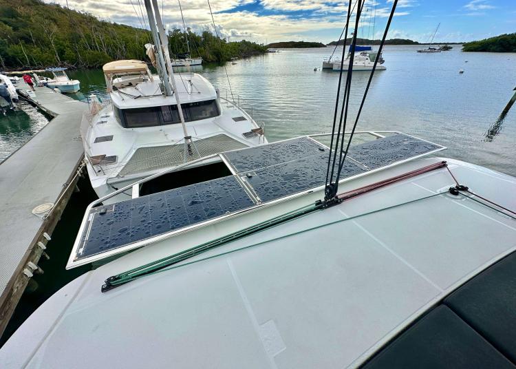 2023 Lagoon 46 catamaran with solar panels docked in a serene marina setting.