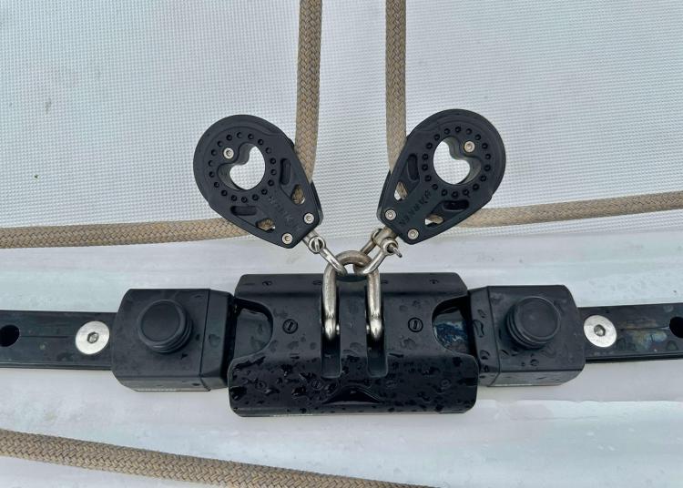 Close-up of a 2023 Lagoon 46 sailboat rigging component with pulleys and metal fittings.