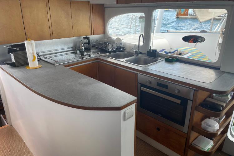 Modern boat kitchen with wooden cabinets, dual sinks, and an oven, overlooking the water.