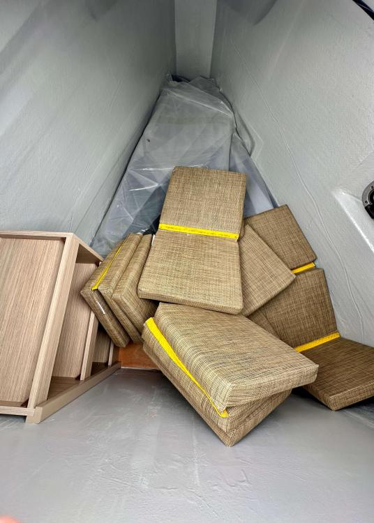 Storage area in a 2023 Lagoon 46 yacht with stacked cushions and wooden panels.