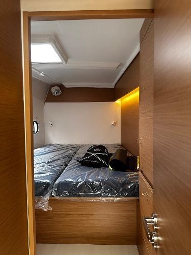 2024 Excess 11 yacht cabin with modern wood finish and cozy bedding.