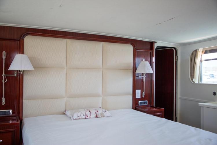 Luxurious bedroom interior on a 1972 Benetti 33 yacht, featuring elegant wood paneling.