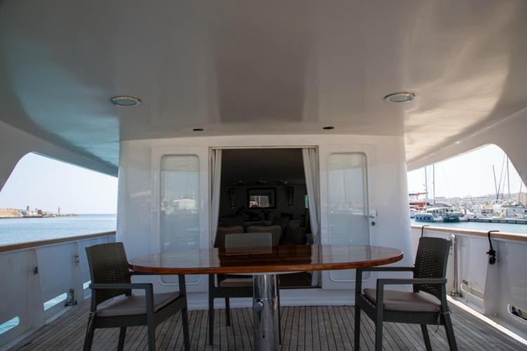 Deck view of 1972 Benetti 33 yacht with table and chairs, overlooking marina.