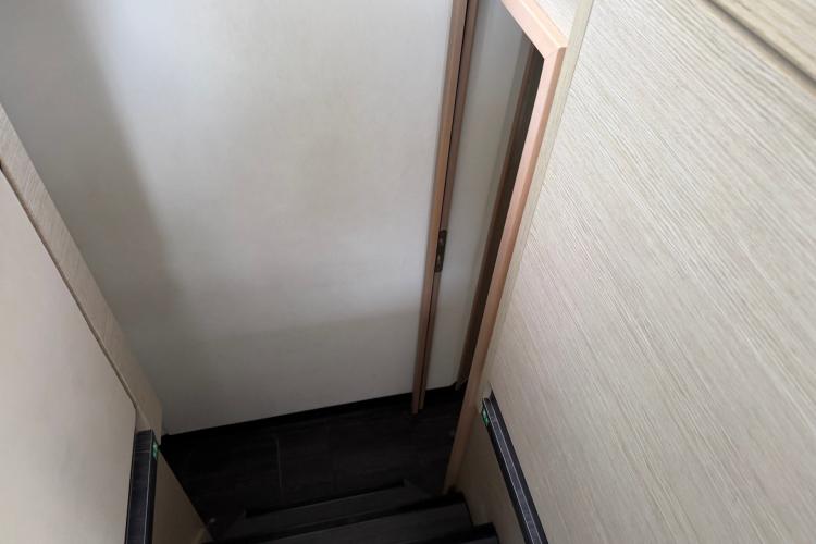 Staircase inside 2020 Fountaine Pajot Astrea 42 catamaran, featuring wooden walls and door.
