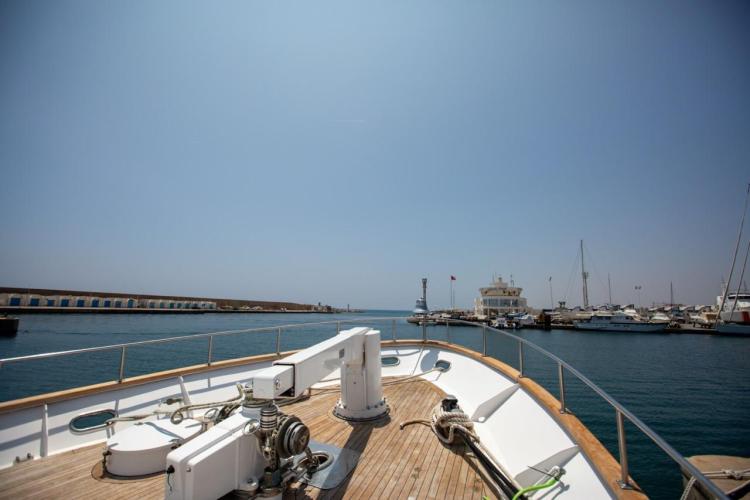 Deck view of 1972 Benetti 33 yacht in a marina, clear sky, calm waters.