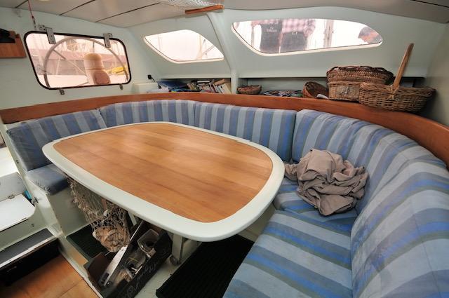 Interior of 2005 Custom Polynésie 42 yacht with striped seating and wooden table.