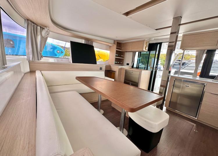 Modern interior of 2023 Lagoon 46 catamaran with dining area and kitchenette.