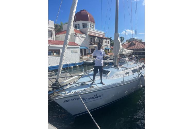 Man standing on 1986 Dufour CATALINA sailboat docked at marina, sunny day.