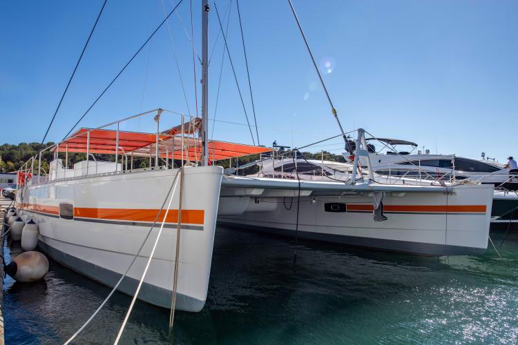 Custom DAYCHARTER 2026 catamaran docked, featuring sleek design and vibrant orange accents.