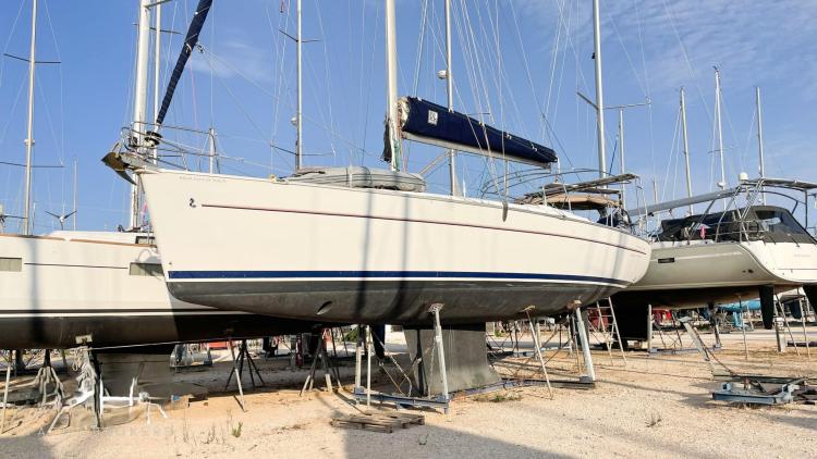 2005 Beneteau Cyclades 43.3 sailboat on dry dock, surrounded by other vessels.