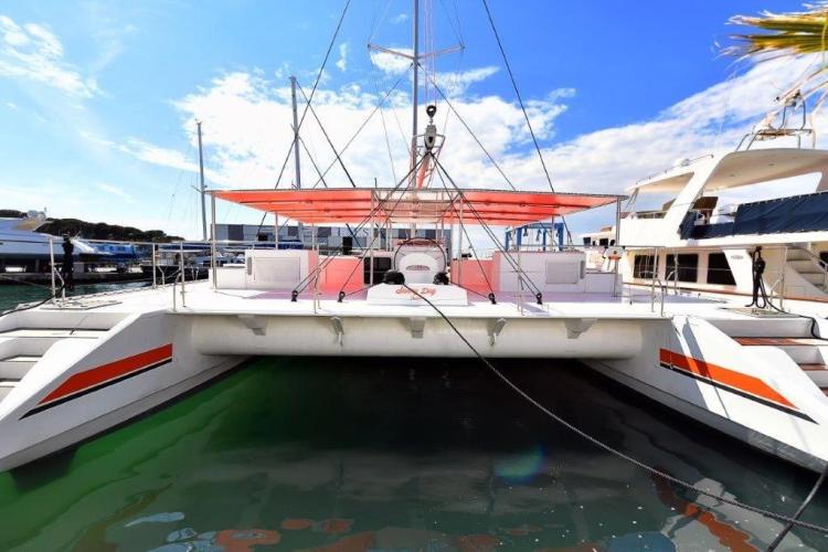 Custom DAYCHARTER 2026 catamaran docked at marina, featuring vibrant red accents and spacious deck.