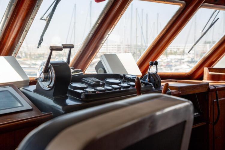 Bridge of a 1972 Benetti 33 yacht with classic wooden controls and panoramic windows.