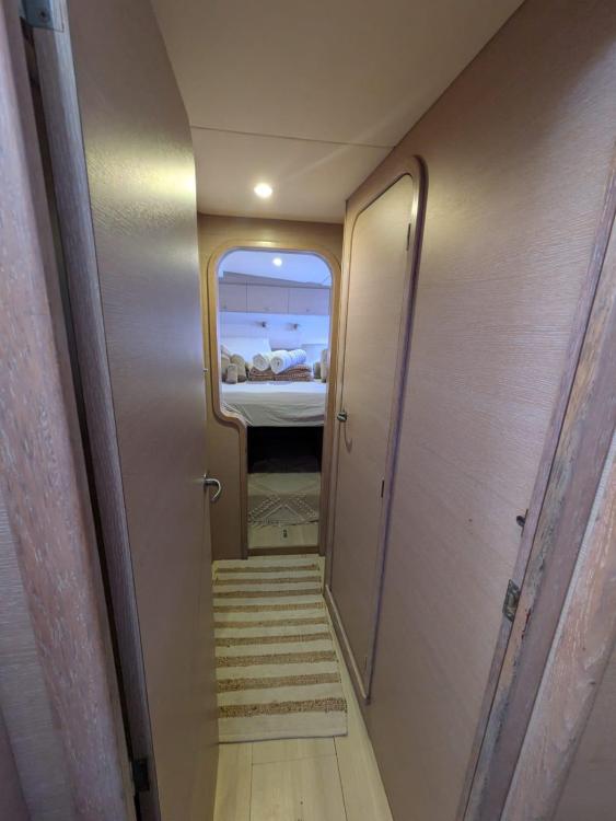 Narrow hallway inside 2012 Catana 55 yacht, leading to a cozy bedroom.