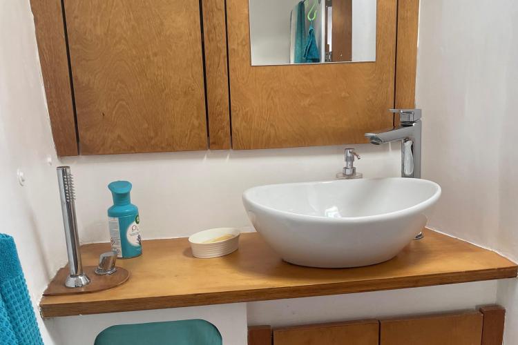 Modern bathroom sink with wooden cabinet, mirror, and toiletries on a Custom KSENIA 149 model.