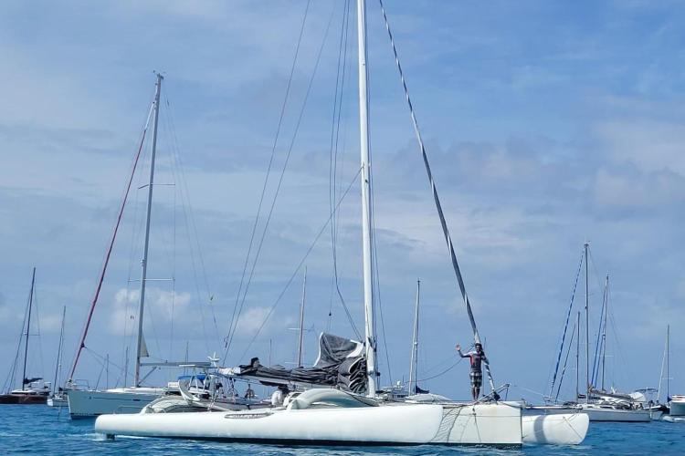 Sailing scene with a 1994 Coulombel Trimaran on calm waters, surrounded by other boats.
