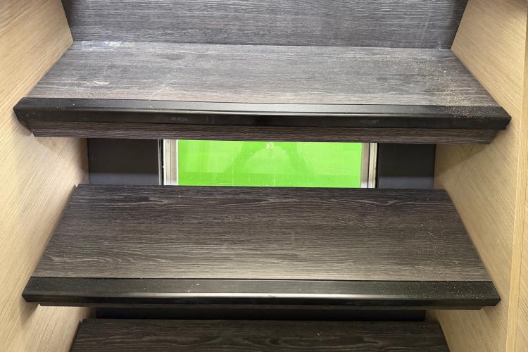Dark wooden stairs with a green window, inside a 2020 Fountaine Pajot Astrea 42.