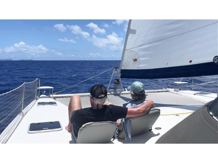 Couple relaxing on a 2006 Fountaine Pajot Bahia 46 catamaran sailing in the ocean.