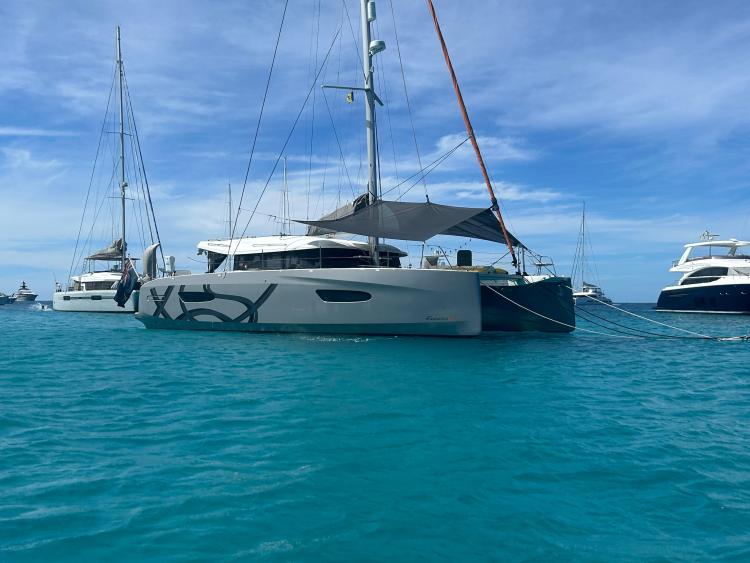 2024 Excess 14 catamaran anchored in clear blue waters under a sunny sky.