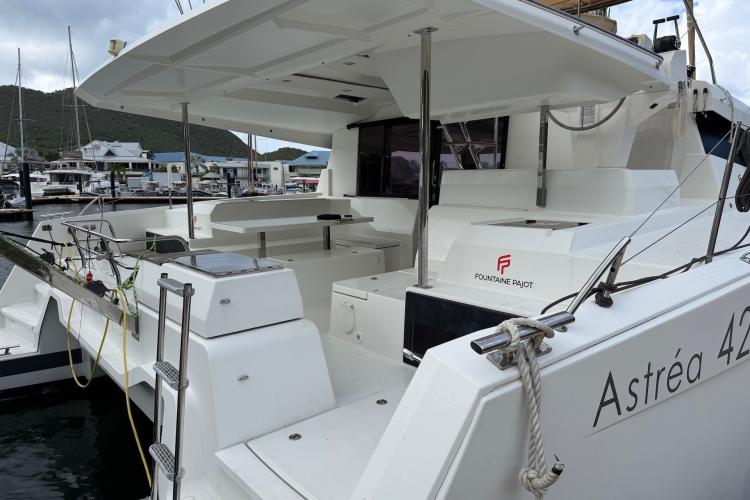 2020 Fountaine Pajot Astrea 42 catamaran docked at marina, showcasing spacious deck and seating area.