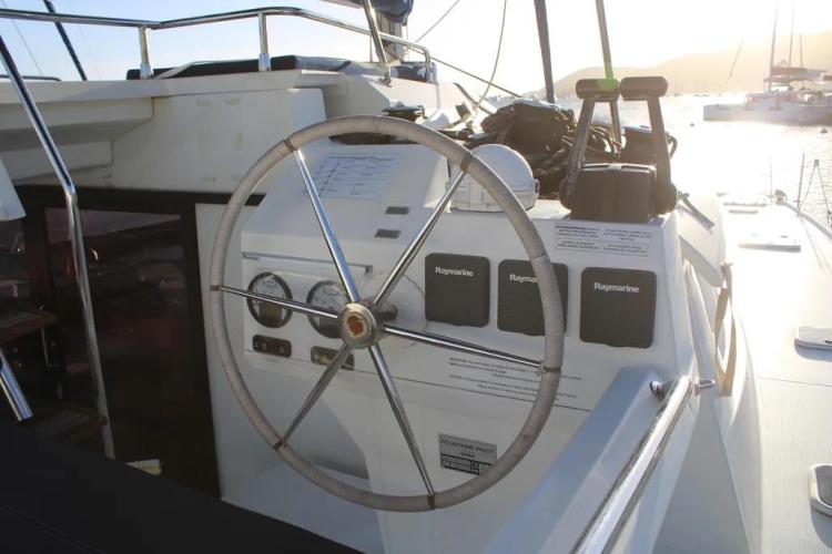 Steering wheel of 2017 Fountaine Pajot SABA 50 catamaran, docked in a sunny marina.