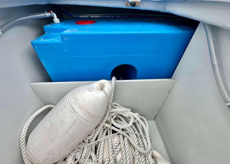 Storage compartment on a 2023 Lagoon 46 yacht with blue tank, rope, and fender.