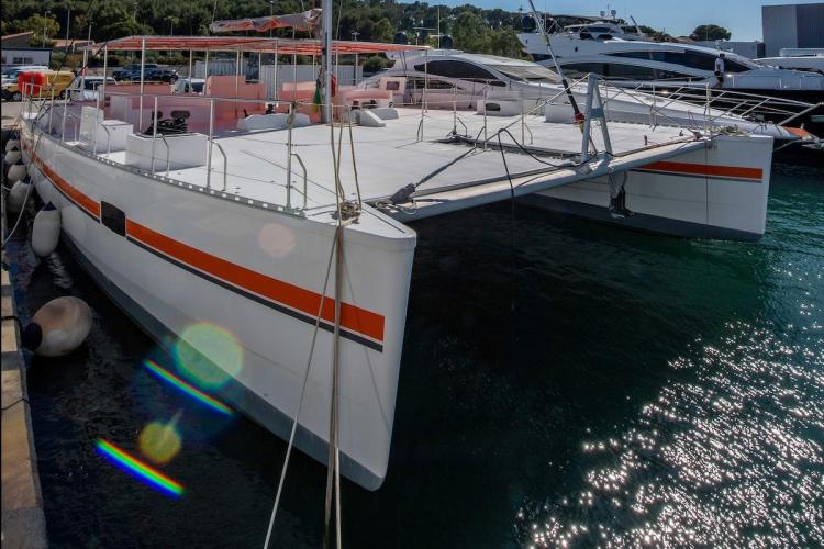 Modern 2026 Custom DAYCHARTER catamaran docked at marina, featuring sleek design and vibrant accents.