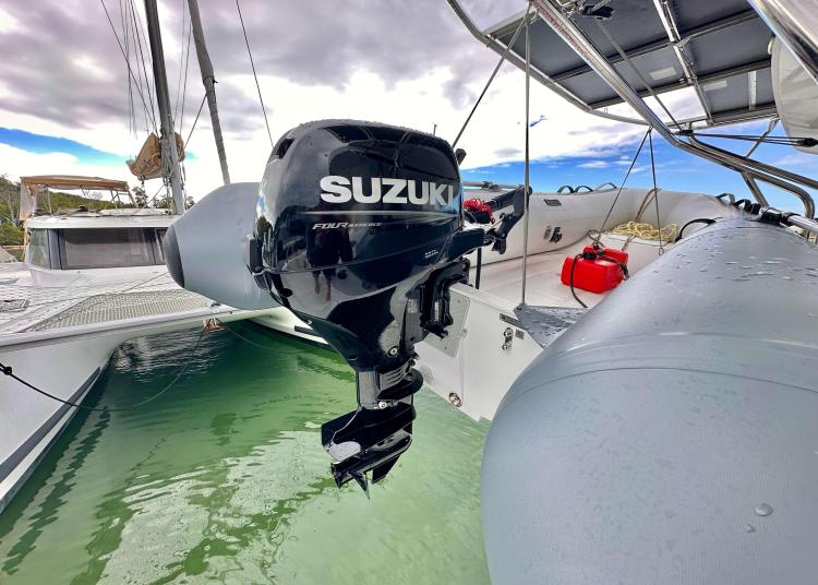 Outboard motor on 2023 Lagoon 46 catamaran, docked in calm waters.