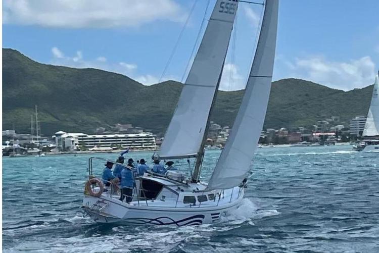 Sailboat Dufour CATALINA 1986 navigating coastal waters with crew, mountains in background.