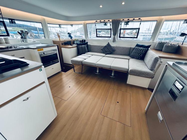 Modern interior of 2024 Excess 14 yacht with spacious seating and kitchen area.