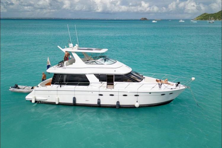 2000 Carver 530 Voyager Pilothouse yacht on turquoise water, with people relaxing onboard.