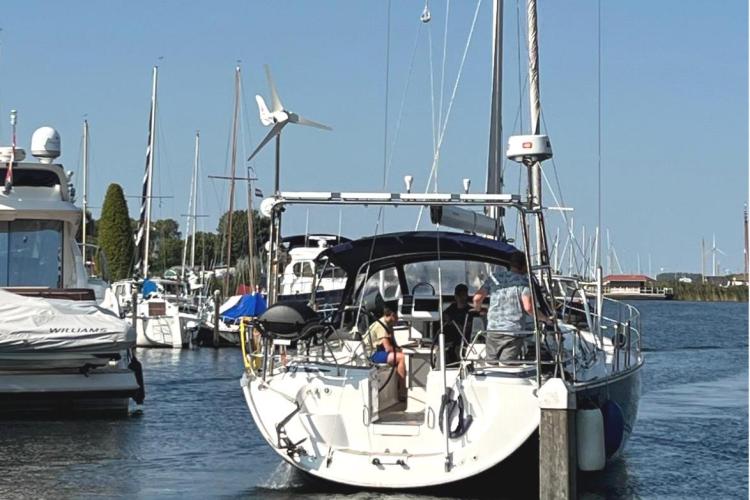 Bavaria Cruiser 46 sailboat from 2006 docked in a marina, with people onboard.