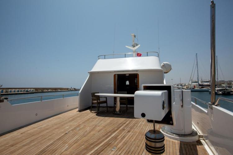Deck view of 1972 Benetti 33 yacht, featuring wooden flooring and marina backdrop.