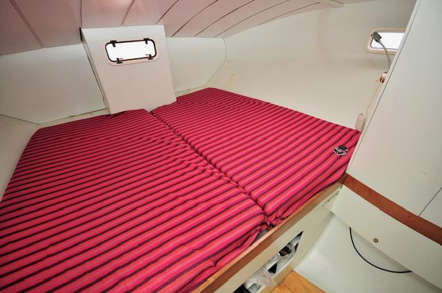 Cozy cabin interior of 2005 Custom Polynésie 42 with striped red bedding.