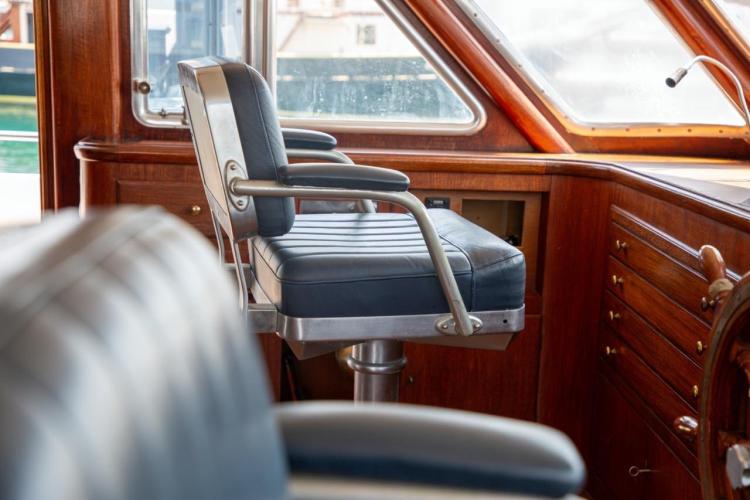 Captain's chair in the helm of a 1972 Benetti 33 yacht, featuring wooden interior.