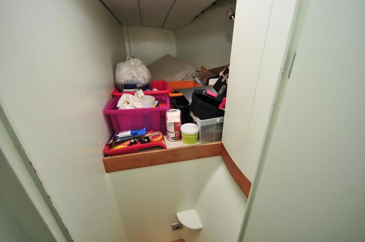 Storage area in a 2005 Custom Polynésie 42 boat with various containers and supplies.