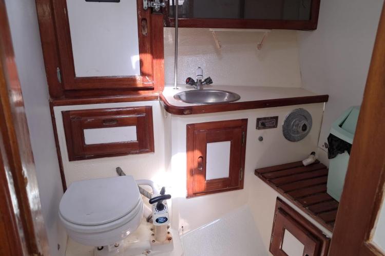 1986 Dufour CATALINA yacht bathroom with wooden cabinets, sink, and toilet.