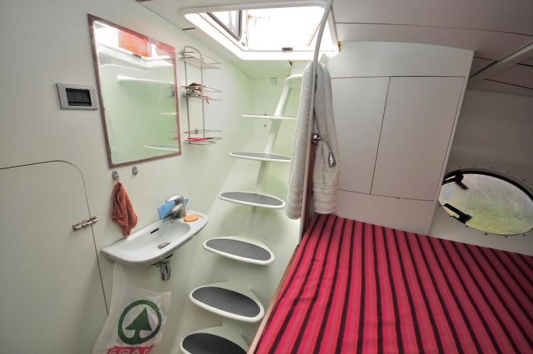 Interior of 2005 Custom Polynésie 42 yacht with stairs, sink, and striped bed.